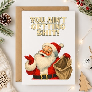 May include: A white greeting card featuring a vintage-style illustration of Santa Claus wearing a red suit with white fur trim, a black belt, and red gloves. Santa holds an empty brown sack. The text reads: YOU AIN'T GETTING SHIT! in bold letters.