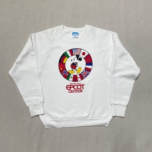 May include: White sweatshirt with a red and blue Mickey Mouse graphic wearing a red shirt and yellow shorts. The graphic is surrounded by a circle of flags from different countries. The text "Walt Disney World® EPCOT CENTER" is printed below the graphic.