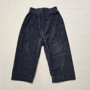 Peut inclure: Un pantalon en velours côtelé bleu marine foncé présentant une texture à côtes verticales et une taille élastiquée. Le pantalon a une coupe droite avec un design simple et épuré, mettant en valeur le tissu texturé sur tout le vêtement.
