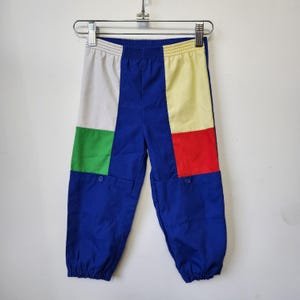 Könnte beinhalten: Farblich abgesetzte Hose mit einer blauen Grundfarbe, einem weißen Feld oben links, einem grünen Feld unten links, einem gelben Feld oben rechts und einem roten Feld unten rechts. Die Hose verfügt über einen elastischen Bund und elastische Beinabschlüsse.