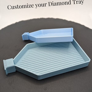 Könnte beinhalten: Zwei Diamant-Maltabletts, eines groß und eines klein. Das große Tablett ist hellgrau mit Marmormuster. Das kleine Tablett ist hellblau mit glänzender Oberfläche. Der Text "Customize your Diamond Tray" befindet sich oben im Bild. Der Text "Model: Ruby" befindet sich unten links im Bild. Der Text "Big Tray: Marble Slate Grey" und "Small Tray: Sky Blue Shiny" befindet sich unten rechts im Bild.