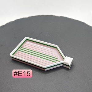 May include: White and pink plastic tray with green lines, designed for organizing small items. The tray is shaped like a bottle and has a small spout. #E15