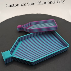 Op de afbeelding: Twee diamant schildertrays, één mintgroen en één roze. De trays zijn ontworpen met rijen richels om diamanten vast te houden. De trays zijn gelabeld "Model: Ronny".