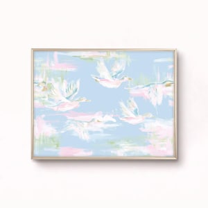 Puede incluir: Una impresión artística enmarcada que presenta una pintura impresionista de varios patos blancos en vuelo sobre un fondo azul claro. La obra utiliza pinceladas suaves y pictóricas en tonos rosa pálido, blanco y verde claro.
