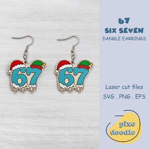 May include: Dangle earrings with the number "67" in a festive design. The earrings feature the number "67" in light blue, with a Santa hat and elf hat, and dripping icing detail. The text "SIX SEVEN" and "DANGLE EARRINGS" are also visible.