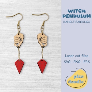 May include: Dangle earrings with a witch theme. Each earring features a hand-shaped charm with black fingernails, a red diamond-shaped pendant, and gold-coloured hooks and chains. The text "Witch Pendulum" is visible.