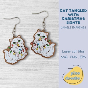 May include: Dangle earrings featuring a white cat tangled in colorful Christmas lights. The cat has green eyes and is set against a brown wooden backing. The earrings are laser cut and include the text "CAT TANGLED WITH CHRISTMAS LIGHTS".