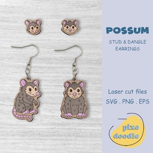 May include: Wooden possum stud and dangle earrings. The earrings feature a cartoon possum design with gray fur, pink ears, and a pink tail. The text "POSSUM STUD & DANGLE EARRINGS" is displayed in blue. The earrings are laser cut files.