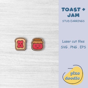 Puede incluir: Un par de pendientes de botón de madera con un diseño de dibujos animados de una tostada y un tarro de mermelada. Los pendientes están cortados con láser y tienen un diseño lindo y caprichoso. El texto "TOAST + JAM STUD EARRINGS" es visible en la imagen.