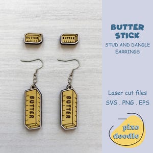 May include: A set of wooden stud and dangle earrings with a butter stick design. The earrings are yellow and brown, with the word "BUTTER" printed on them. The image also includes the text "BUTTER STICK STUD AND DANGLE EARRINGS".