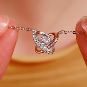 Puede incluir: Un collar de plata con un colgante en forma de corazón que presenta un cristal transparente y la inscripción "Good Girl".