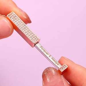 May include: A rose gold necklace with a crystal-encrusted bar pendant that opens to reveal the inscription "Forever & Always".