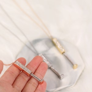 May include: Three gold, silver, and rose gold necklaces with a bar pendant encrusted with clear rhinestones. The bar pendant has a small square at the end with the word "CumSlut" engraved on it.