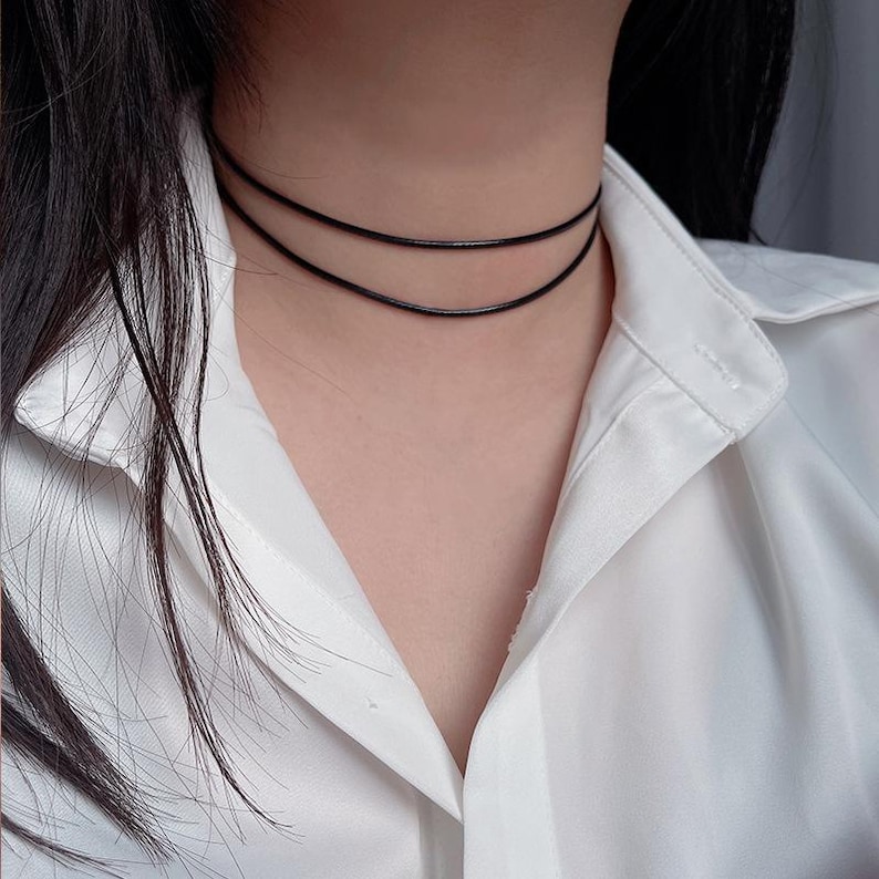 May include: A simple black leather choker necklace with two layers.