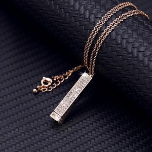 May include: A gold-tone necklace with a long, rectangular pendant encrusted with clear rhinestones.