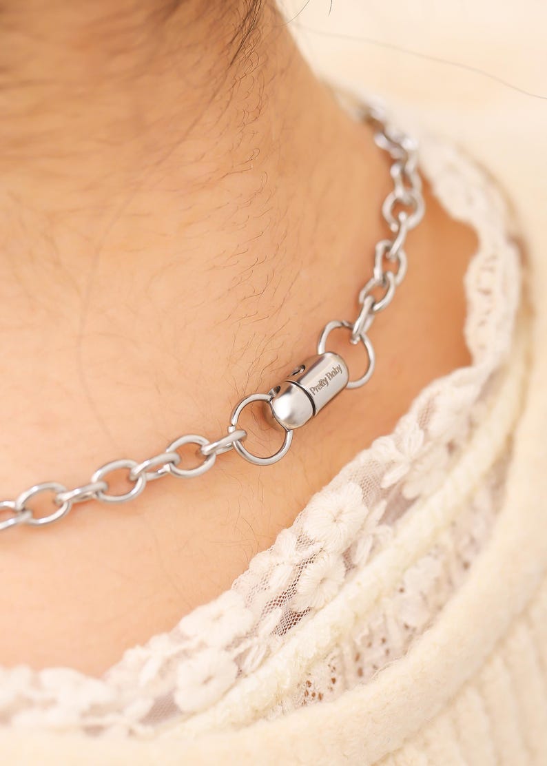May include: A silver chain necklace with a magnetic clasp. The clasp has the text "Pretty Baby" engraved on it.