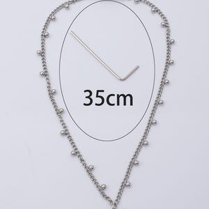 May include: Silver-toned necklace with a bow pendant. The necklace is 35cm (13.8 inches) long and features small ball accents along the chain. A small wrench is included. The necklace has a clasp closure.