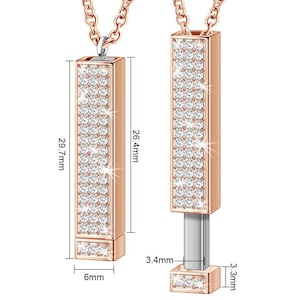 May include: A rose gold pendant necklace with a rectangular charm that is fully covered in clear cubic zirconia stones. The charm is 6.7 cm tall and 1.5 cm wide. The pendant is on a chain that is 75.4 cm long.