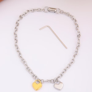 May include: A silver chain bracelet with two heart charms, one gold and one silver.