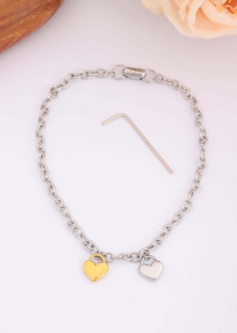 May include: A silver chain bracelet with two heart charms, one gold and one silver.