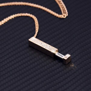 May include: A gold chain necklace with a rectangular pendant encrusted with clear rhinestones. The pendant opens to reveal a small compartment with the word "Mistress" engraved inside.