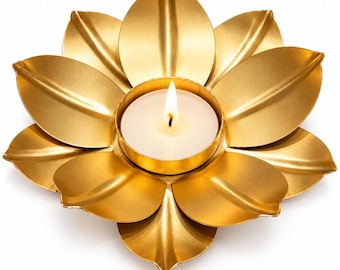 May include: A gold-colored metal candle holder shaped like a blooming lotus flower with layered petals. A small, round, white tea light candle sits in the center, featuring a lit flame that emits a soft, warm glow from the wick.
