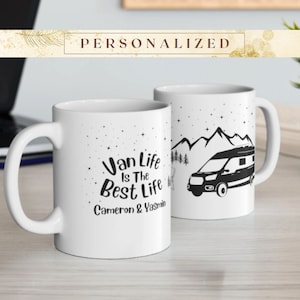 May include: Two white ceramic mugs. One mug features the text "Van Life Is The Best Life" with the names "Cameron & Yasmin" below. The other mug has a black graphic of a camper van, mountains, and trees.