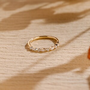 May include: A delicate gold band ring with a row of small, sparkling diamonds set in a pave setting.