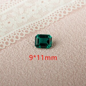 May include: A dark green emerald gemstone with a rectangular cut. The gemstone measures 9 by 11 millimeters.