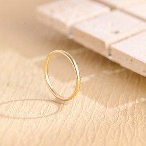 May include: A simple gold band ring. The ring is thin and has a smooth, polished finish.