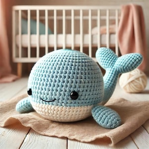 Puede incluir: Un juguete de peluche de ballena de ganchillo azul y blanco con ojos de seguridad negros y una boca sonriente. La ballena está sobre una tela beige, con una cuna y una madeja de lana en el fondo. Un lindo juguete para bebés hecho a mano.