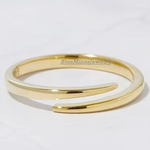 Peut inclure: Une bague en or avec un design unique. La bague est faite d'une seule pièce de métal qui est tordue et enroulée autour du doigt. La bague est simple et élégante.