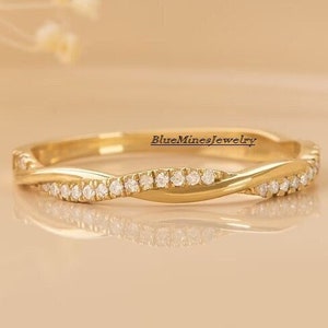 May include: A delicate gold band ring with a twisted design and a row of small diamonds set along the edge.