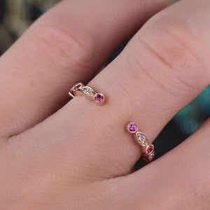Op de afbeelding: Een delicate gouden ring met een gebogen ontwerp met afwisselende roze en witte edelstenen.