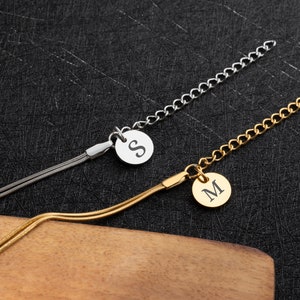 May include: Two gold and silver chain necklaces with a round pendant featuring the letters "S" and "M" engraved on them.