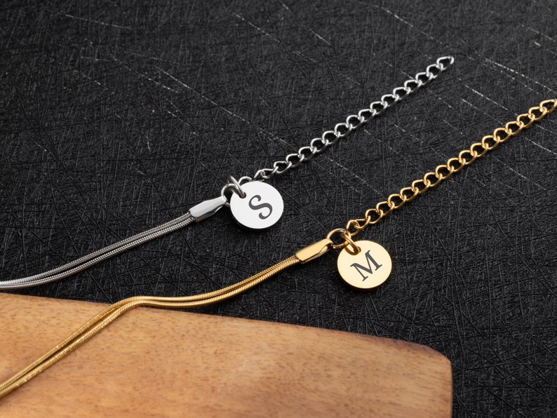 May include: Two gold and silver chain necklaces with a round pendant featuring the letters "S" and "M" engraved on them.