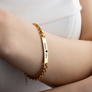 May include: Gold chain bracelet with a personalized nameplate that reads "Laura &hearts; Alex".