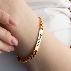 May include: Gold chain bracelet with a rectangular tag that says "Your Message".