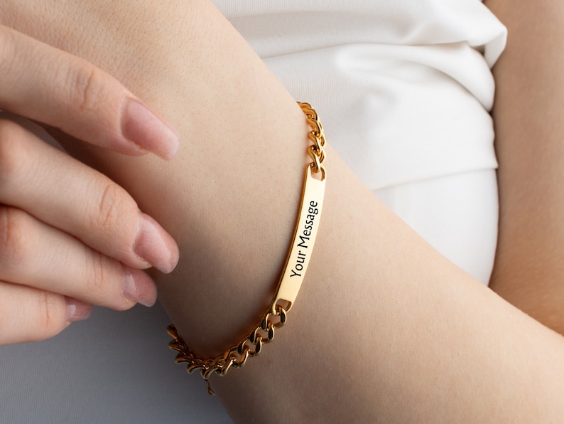 May include: Gold chain bracelet with a rectangular tag that says "Your Message".
