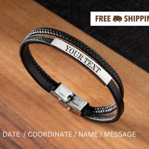 May include: Black leather bracelet with a silver plate that says "YOUR TEXT". The bracelet is on a wooden surface.