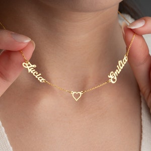 May include: Gold necklace with two names, "Lucia" and "Emilia", separated by a small heart charm.
