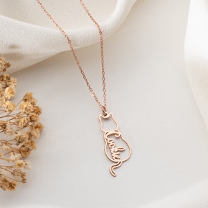 Op de afbeelding: Roze gouden ketting met een hanger in de vorm van een katten silhouet. De hanger heeft de naam "Cookie" geschreven in het lichaam van de kat.