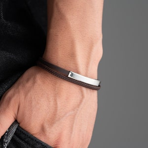 May include: A brown leather bracelet with a silver metal band.