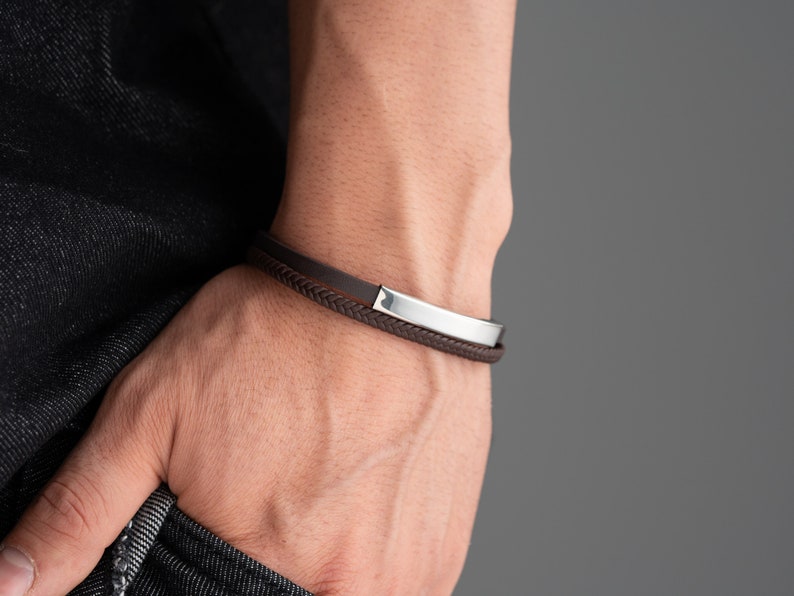 May include: A brown leather bracelet with a silver metal band.