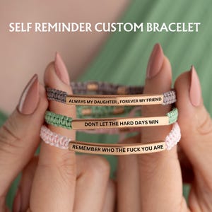 May include: Three bracelets with different colored cords and gold metal bars with inspirational messages. The messages are "Always my daughter, forever my friend", "Don't let the hard days win", and "Remember who the f*** you are".