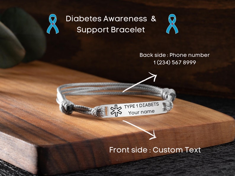 May include: A gray diabetes awareness bracelet with a metal plate. The plate is engraved with "TYPE 1 DIABETS" and space for a custom name. The bracelet is on a wooden surface. Text on the image reads "Diabetes Awareness & Support Bracelet".