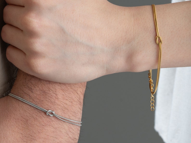 May include: Two matching bracelets with a knot design. One bracelet is silver and the other is gold.