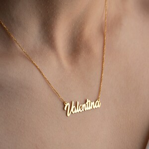 May include: A gold chain necklace with a cursive nameplate pendant that reads "Valentina".