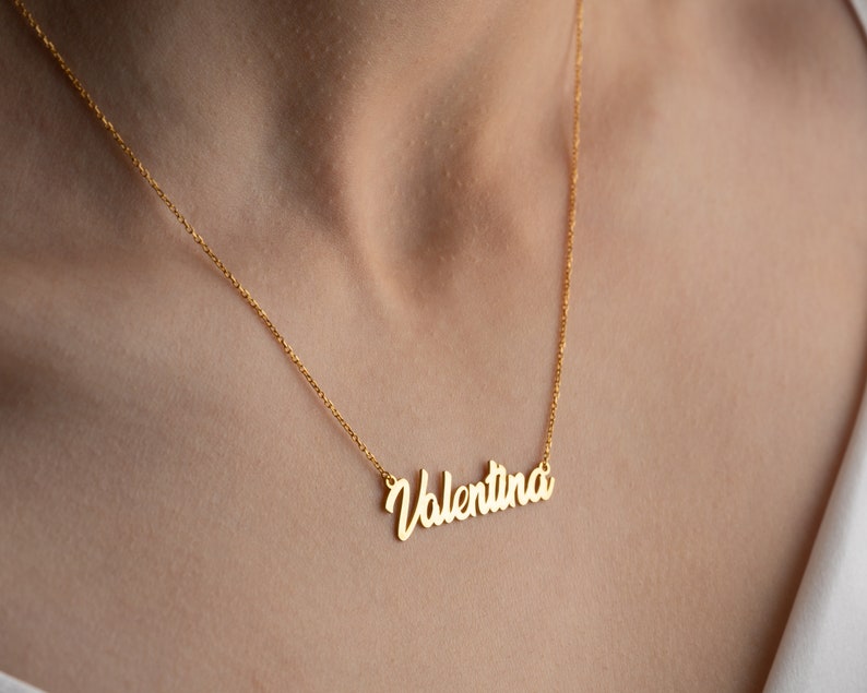 May include: A gold chain necklace with a cursive nameplate pendant that reads "Valentina".