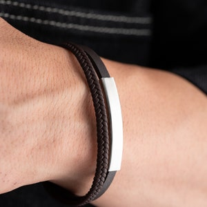 May include: A brown leather bracelet with a silver bar accent.